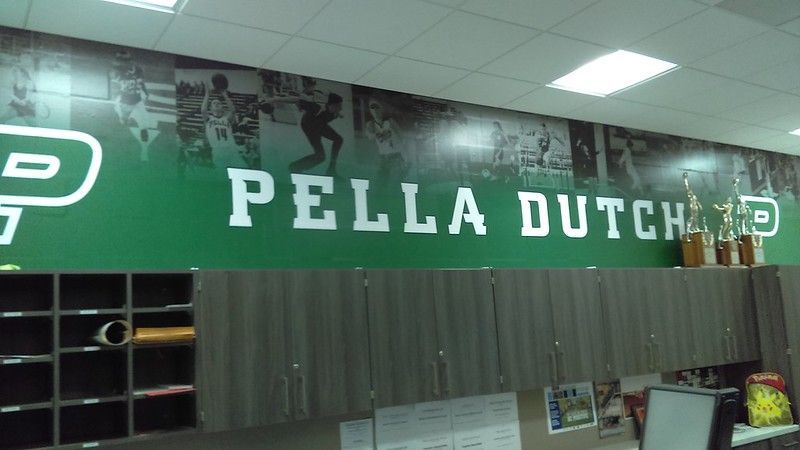 A green wall with a mural of athletes, the text 