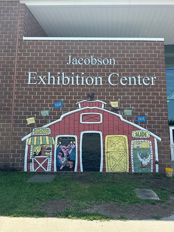 A red barn mural painted on a brick wall labeled 