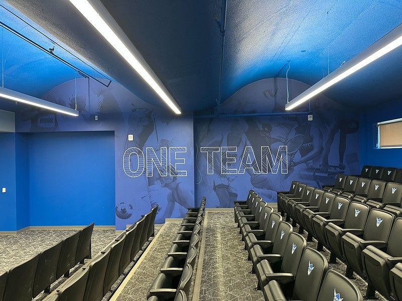 A blue-walled room with rows of theater seats facing a wall that says 