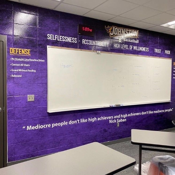 A purple classroom wall features a whiteboard, 