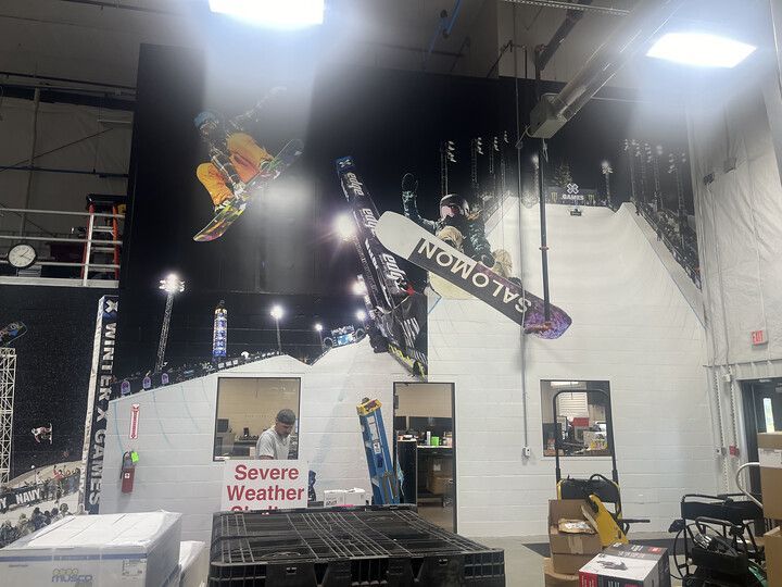 A large wall mural of snowboarders mid-air hangs above an indoor office space with a 