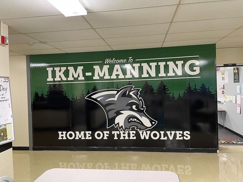 A wall graphic in a school hallway with a wolf mascot logo, reading 