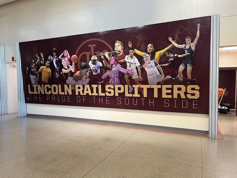 Large banner for Lincoln Railsplitters featuring various student athletes and performers in a school hallway.