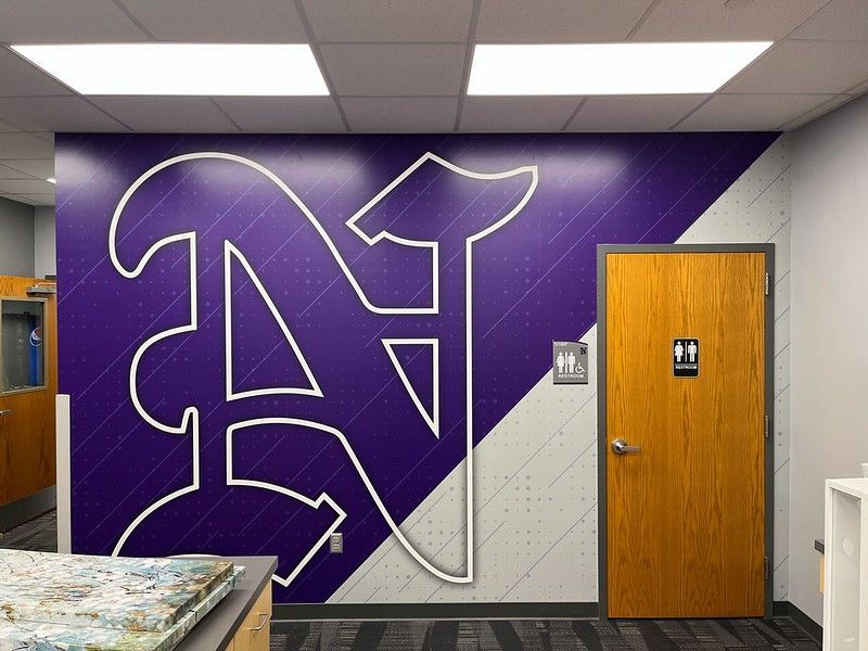 A purple wall with a large white letter 