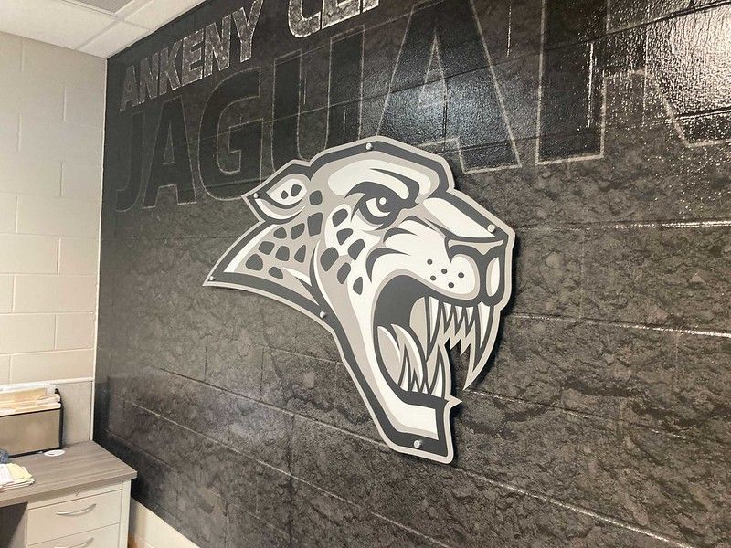 Ankeny Centennial Jaguars logo on a black textured wall featuring an aggressive jaguar head in shades of gray.