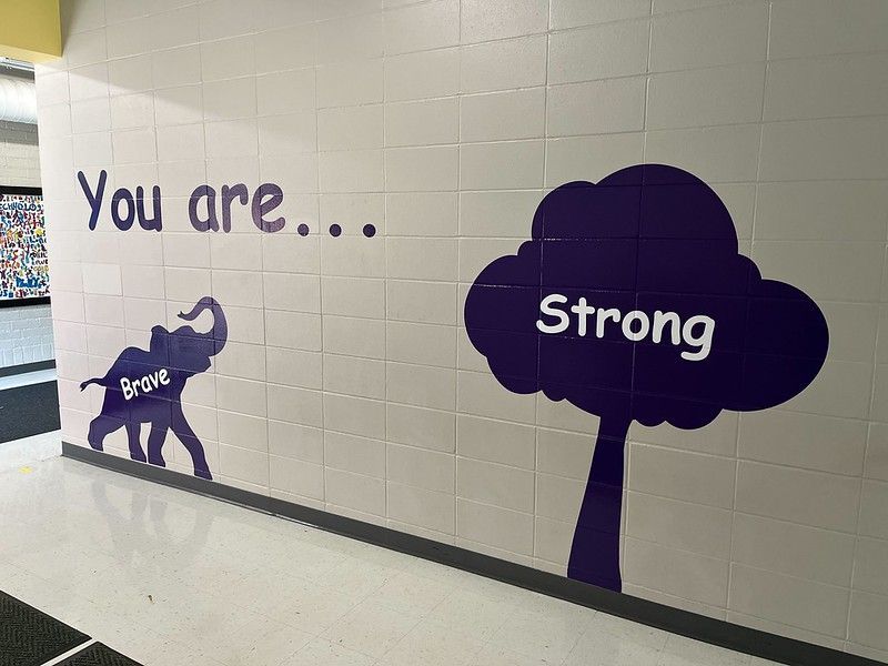 A hallway wall mural in purple text and silhouettes reading 