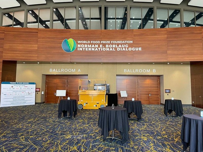 The Norman E. Borlaug International Dialogue venue with Ballrooms A and B, featuring a yellow lift and black-covered tables.