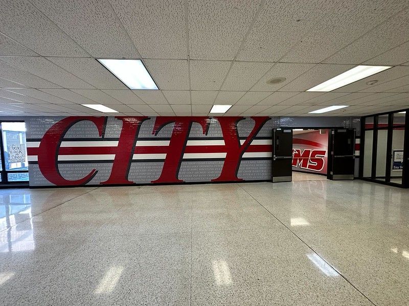 A wide, brightly lit school hallway with a large red 