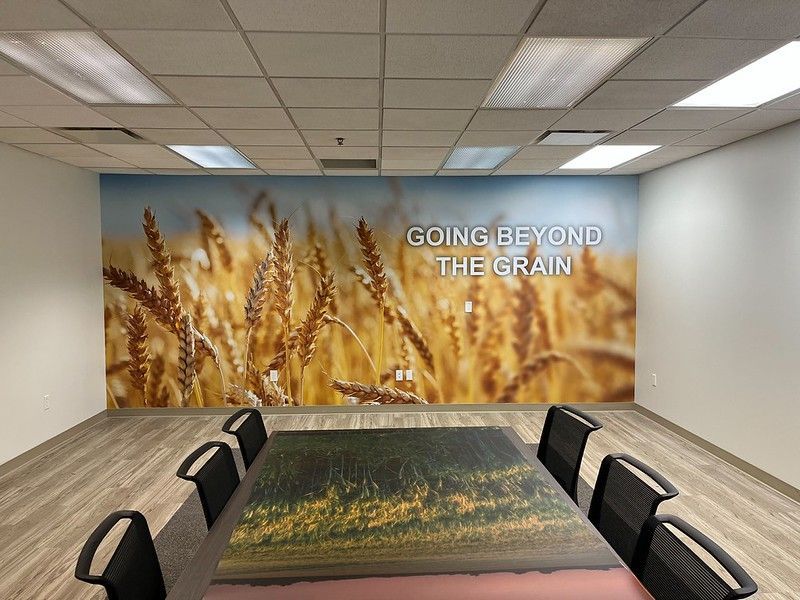 A conference room features a large wall mural of golden wheat fields with the text 