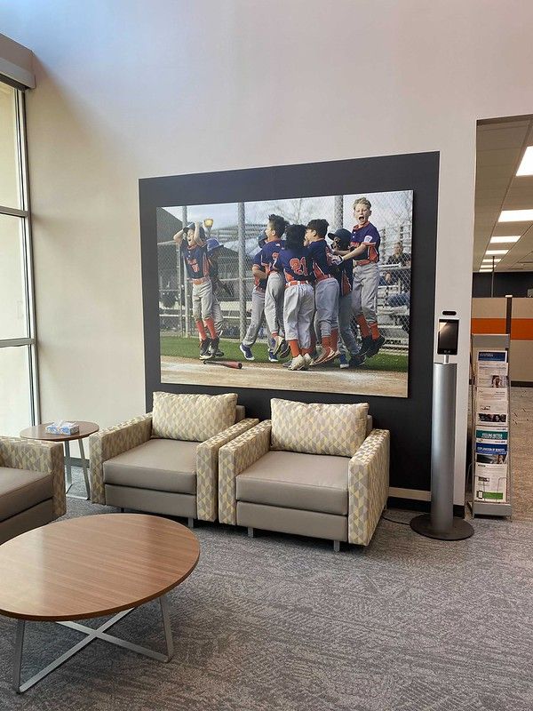Two armchairs in a lobby sit beneath a large framed photo of a baseball team celebrating on a field.