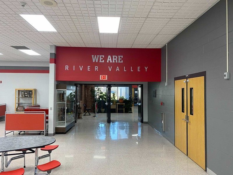 A brightly lit school hallway with a red sign reading 