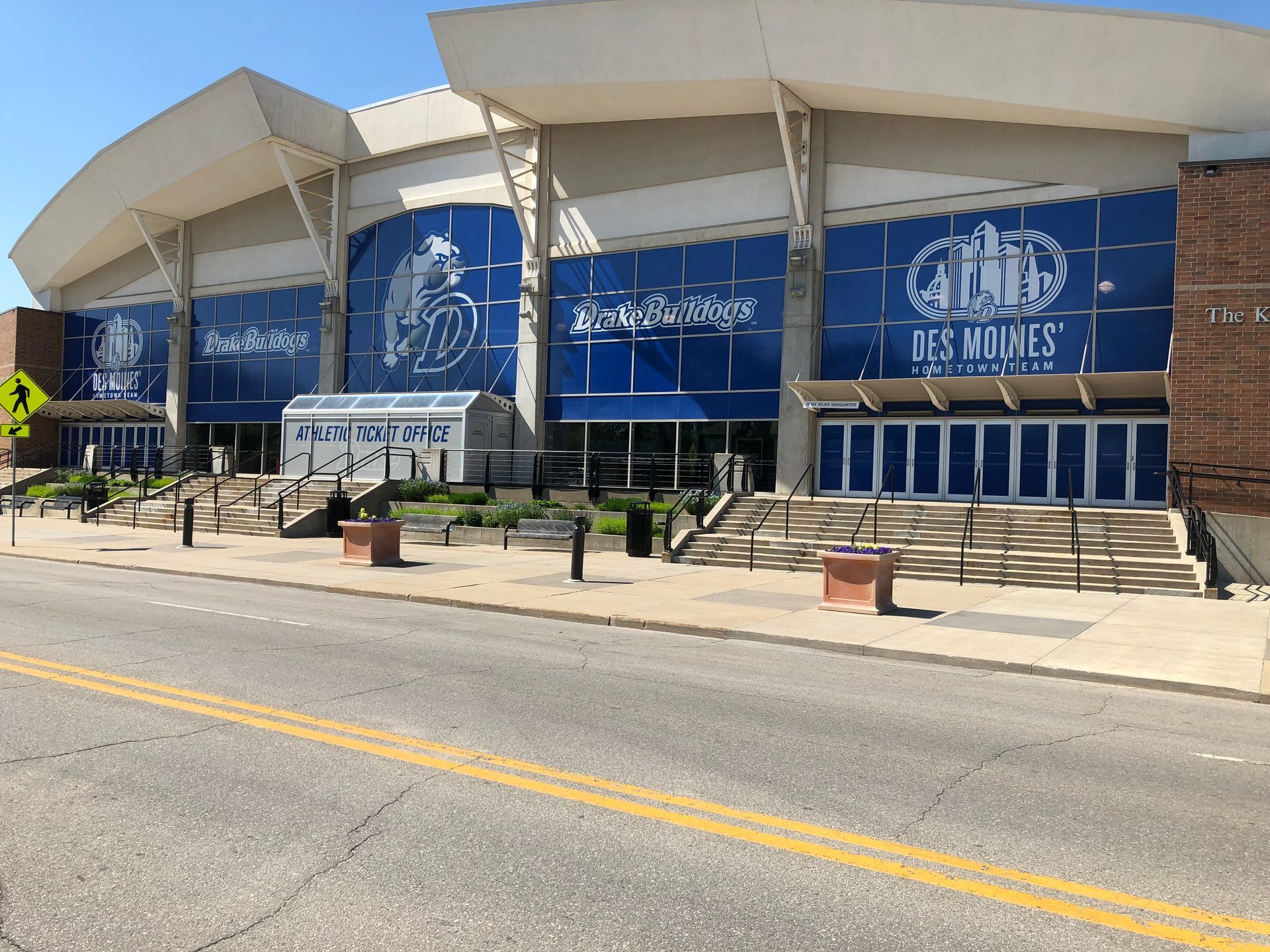 Exterior view of the Des Moines Civic Center with blue-tinted windows, a central ticket office, and concrete steps.