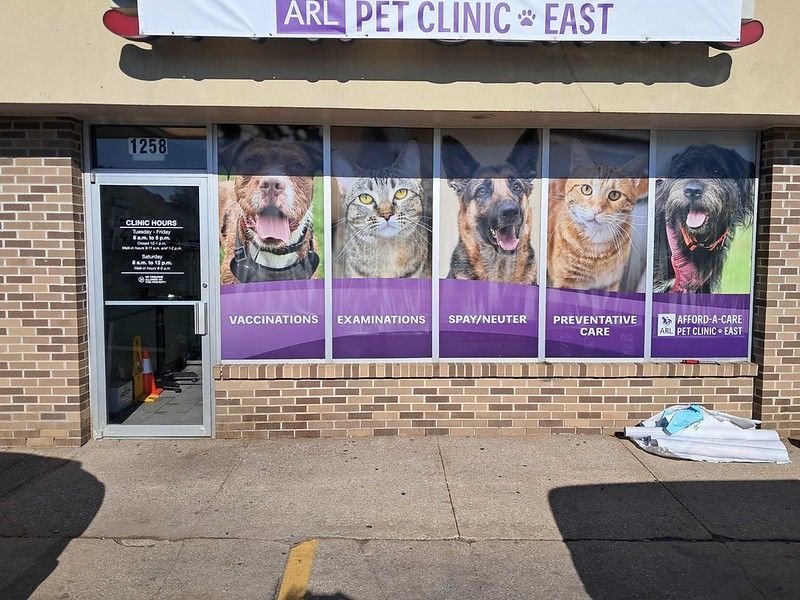 The ARL Pet Clinic at East storefront featuring large window decals of pets and a purple banner with clinic services.