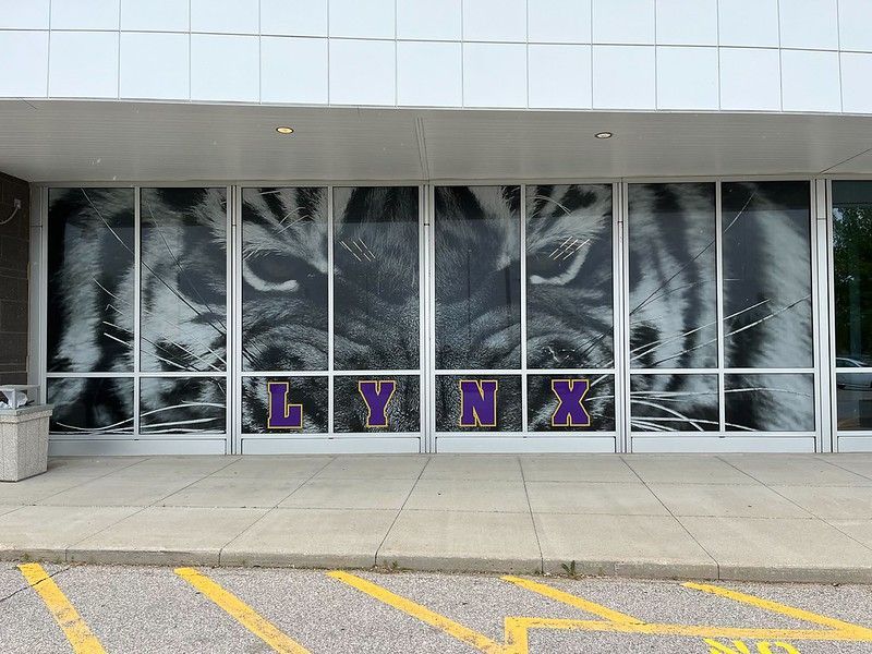 A building entrance with large glass windows featuring a tiger face graphic and the purple text 