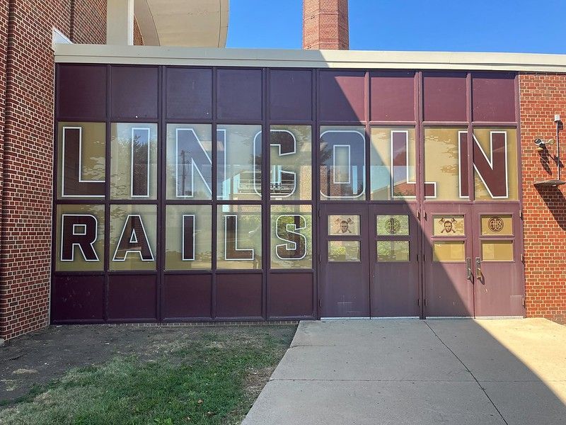 A brick school building exterior with maroon glass panels featuring the white lettering 