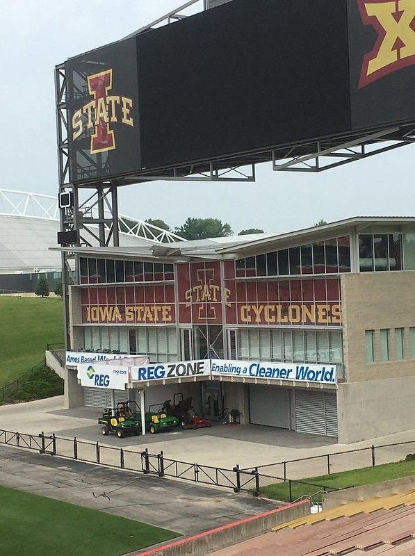 A view of the Iowa State University stadium scoreboard and building with maintenance vehicles parked underneath.