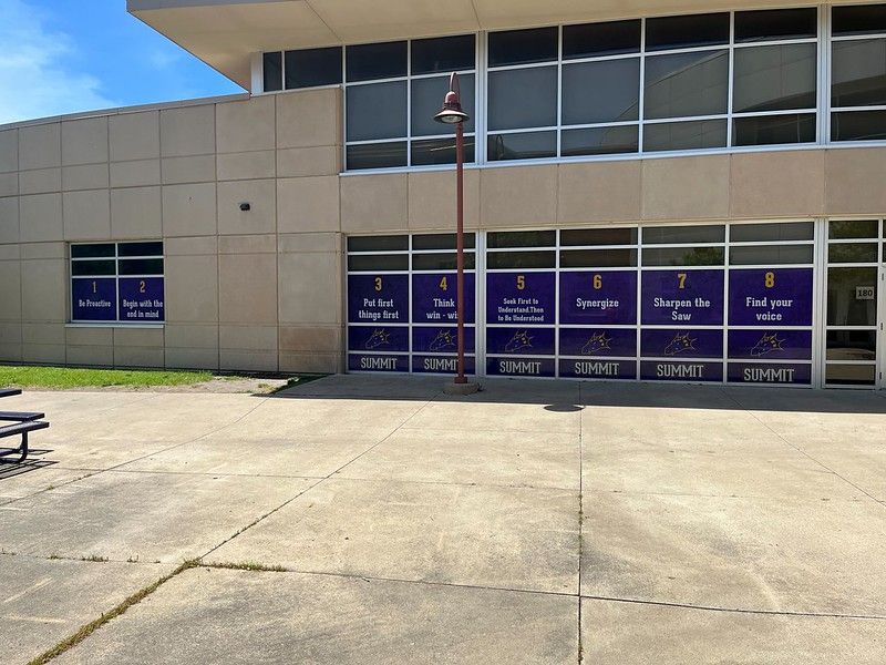 An exterior view of a building featuring eight numbered window decals with text, including the word 