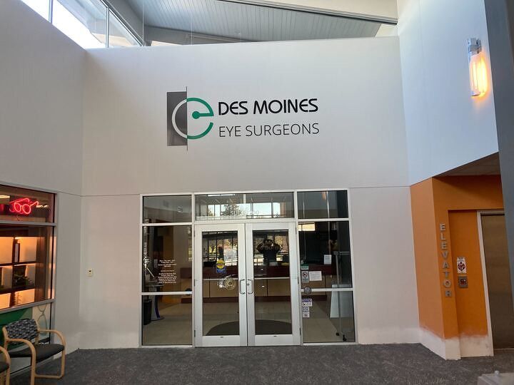 The entrance to Des Moines Eye Surgeons, featuring a white wall with the company logo and glass double doors.
