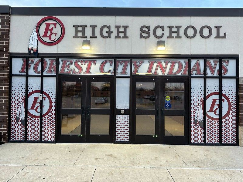 The entrance to Forest City High School with double glass doors, school branding, and an Indians mascot logo.