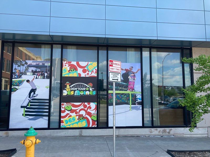 Skateboarding-themed window decals on a modern building in downtown Des Moines, Iowa, beside a yellow fire hydrant.
