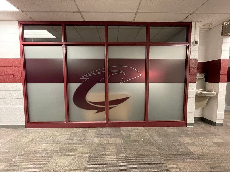 The Cleveland Cavaliers logo on frosted glass office windows in a hallway with a water fountain to the right.