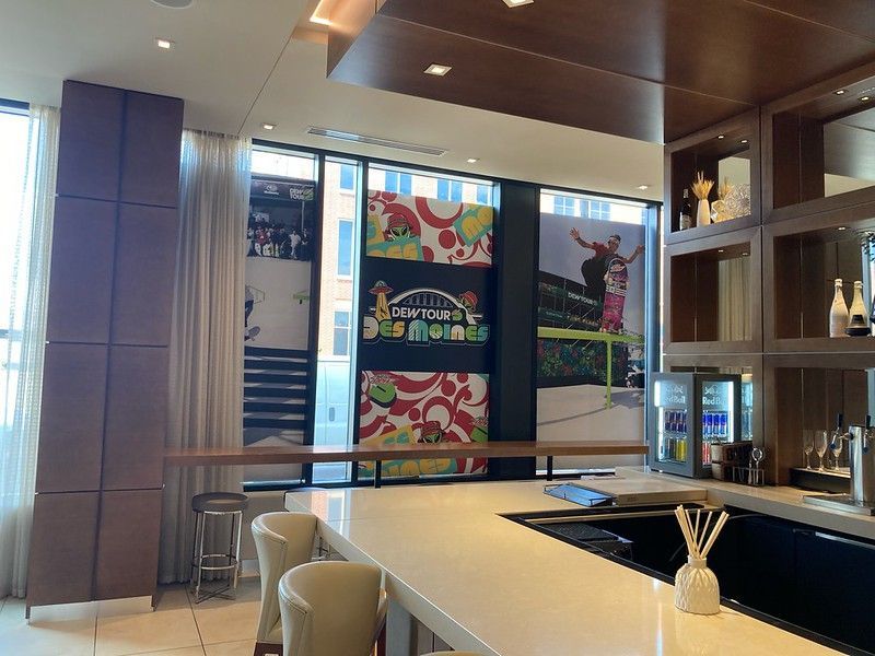 A contemporary bar with a white counter, cream-colored chairs, and large window decals featuring colorful graphic art.