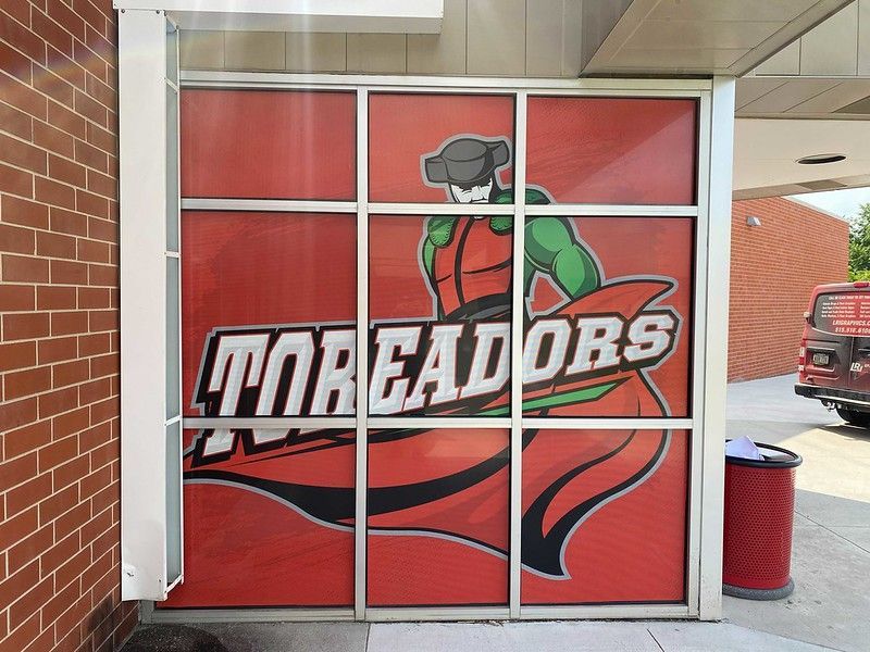 A window display featuring a mascot in a red matador outfit with the word 