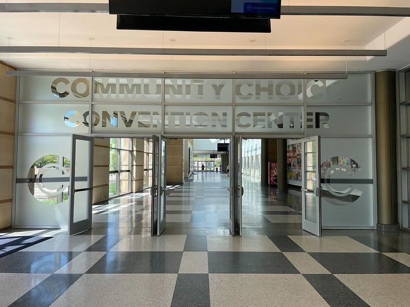 Entrance to the Community Choice Convention Center, featuring glass doors and a white and grey tiled floor.