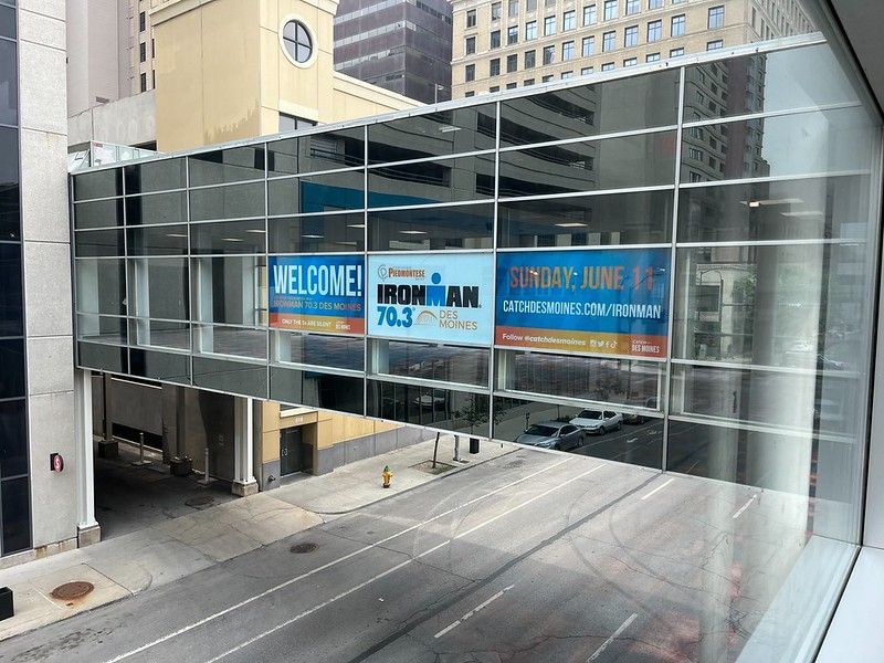 A skywalk with a banner for the IRONMAN 70.3 triathlon event spanning across a city street.