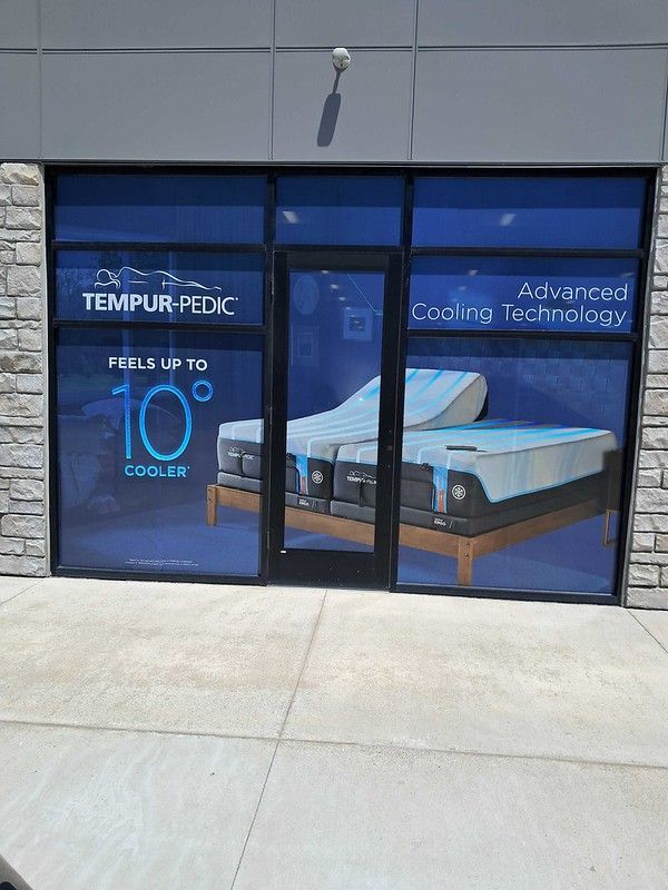 A Tempur-Pedic storefront window displaying an adjustable bed and advertising cooling technology that feels 10° cooler.