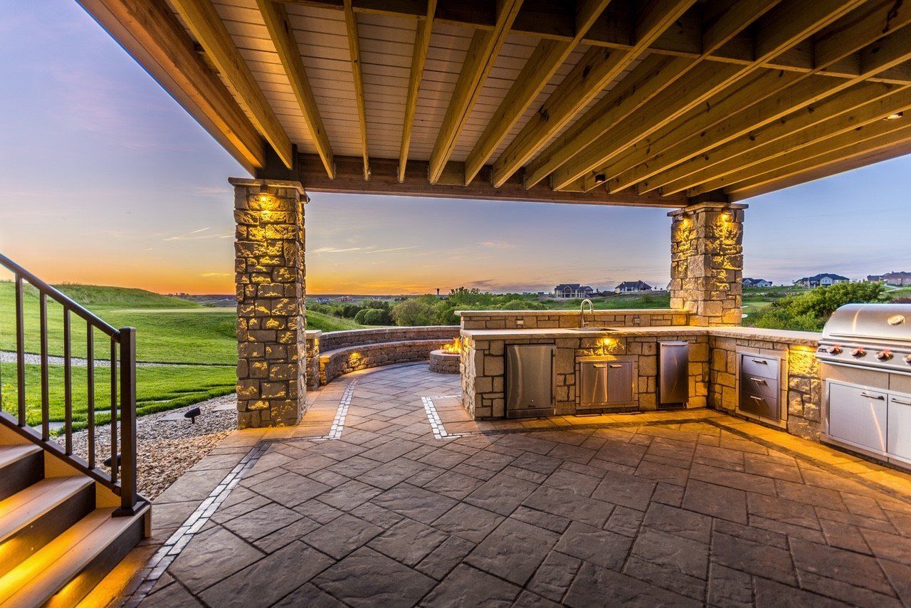 A patio with a grill and a view of a golf course.