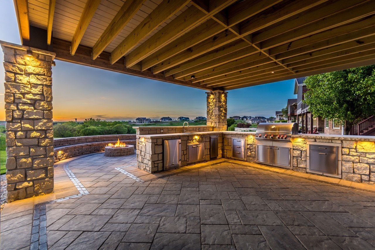 A large outdoor kitchen with a covered patio and a fire pit.