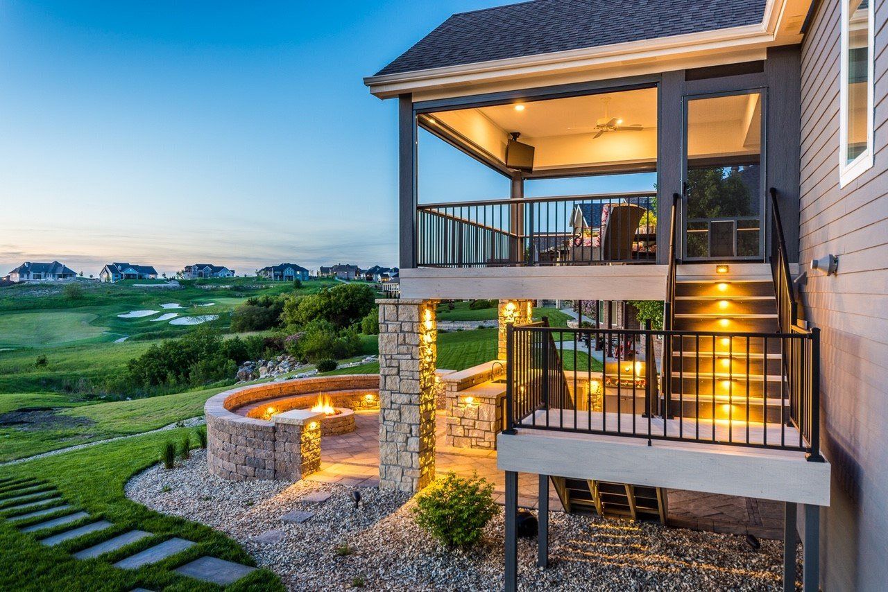 A house with a large deck and a fire pit in the backyard.