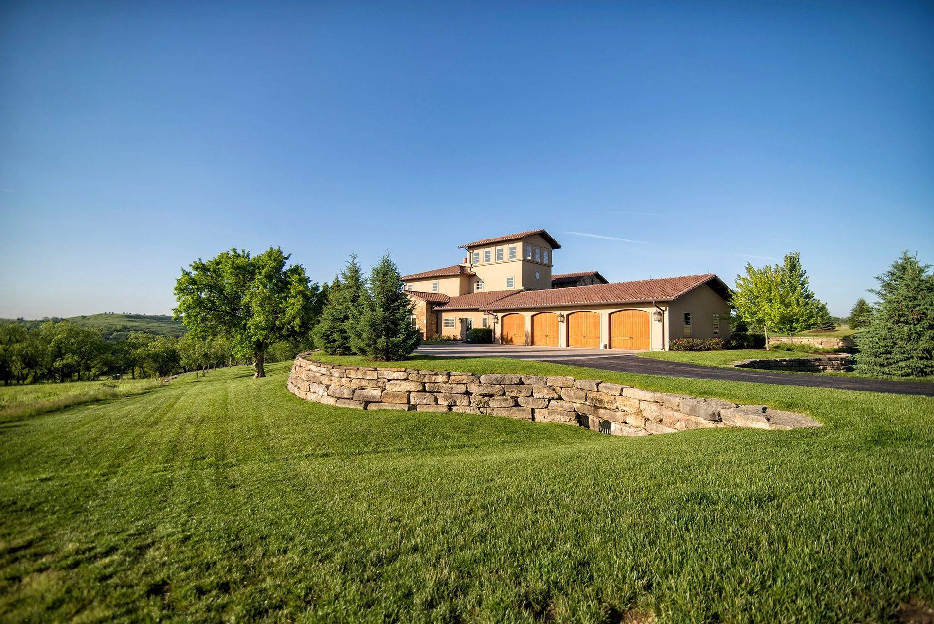 A large house is sitting in the middle of a lush green field.