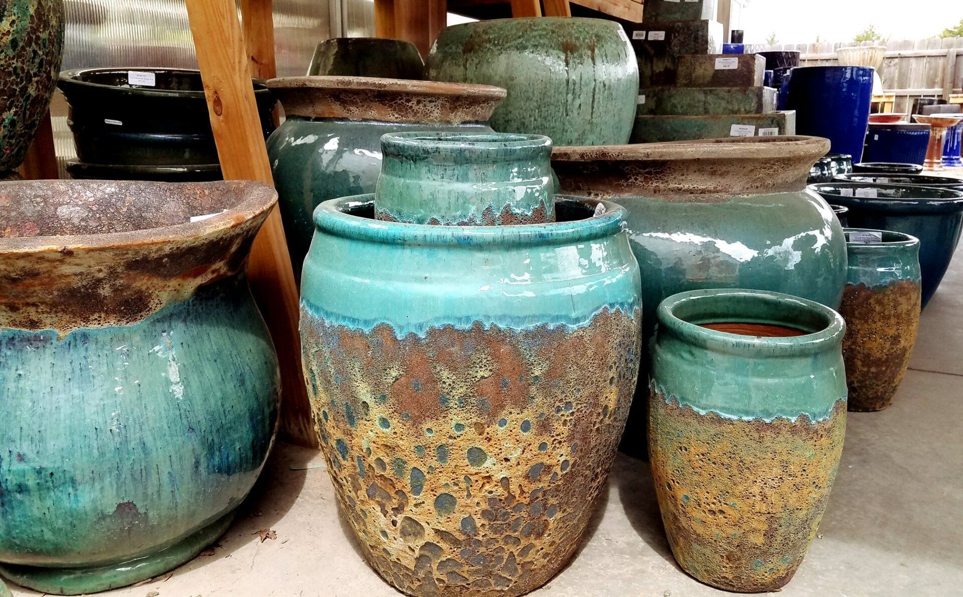 A bunch of green and brown pots are sitting on the ground