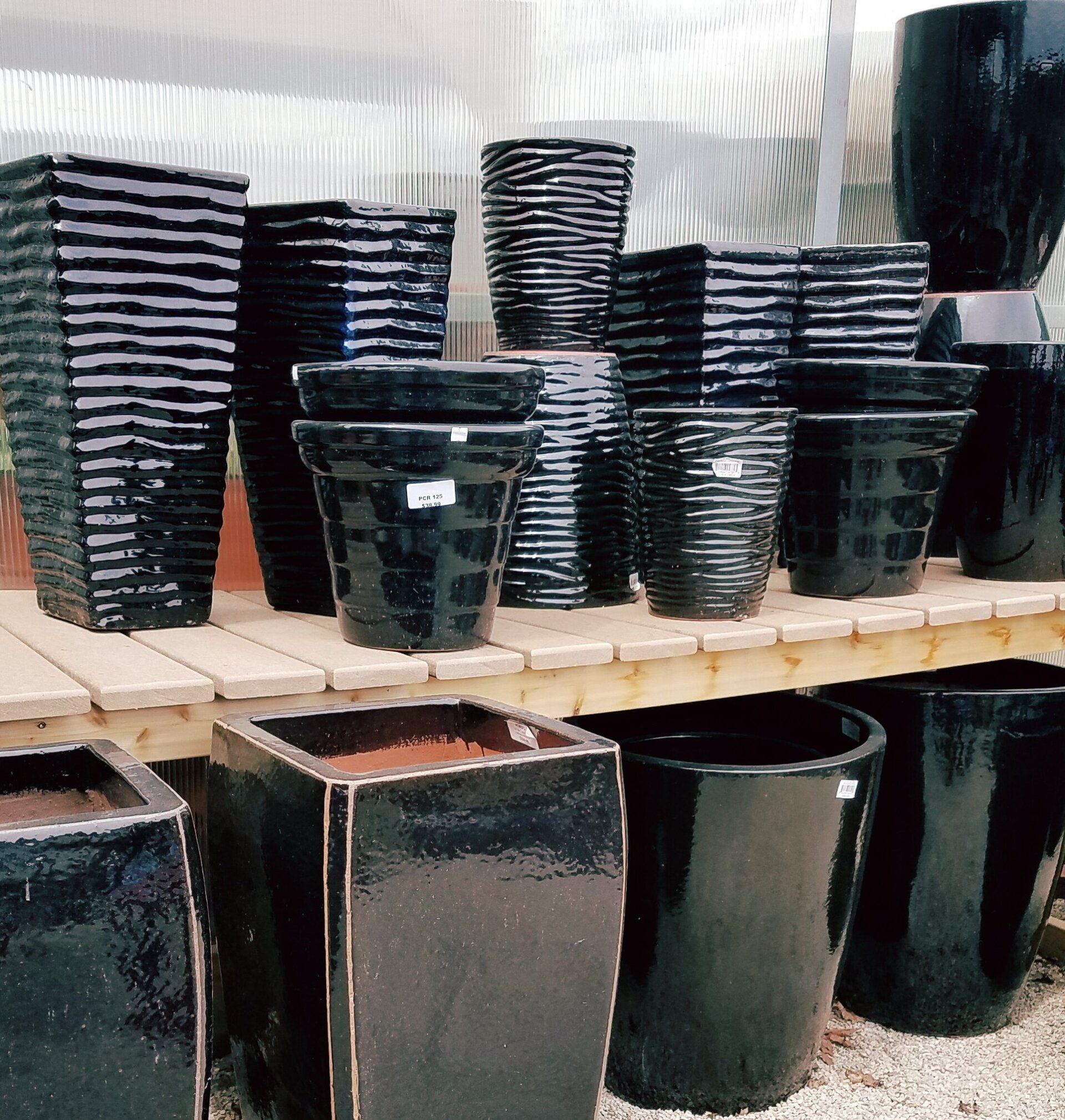 Many black pots are lined up on a wooden shelf