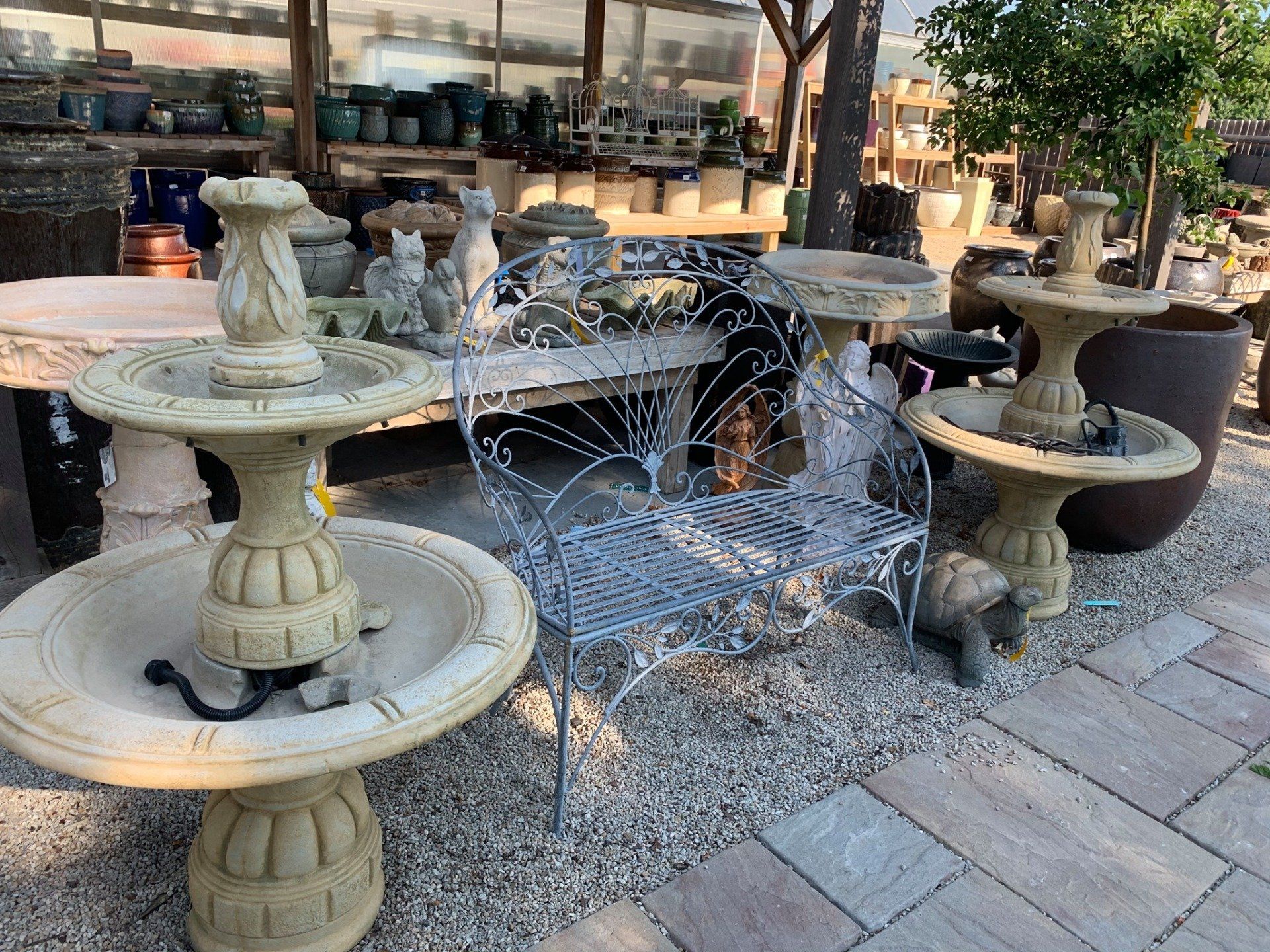 A group of fountains and chairs are sitting on a brick sidewalk.