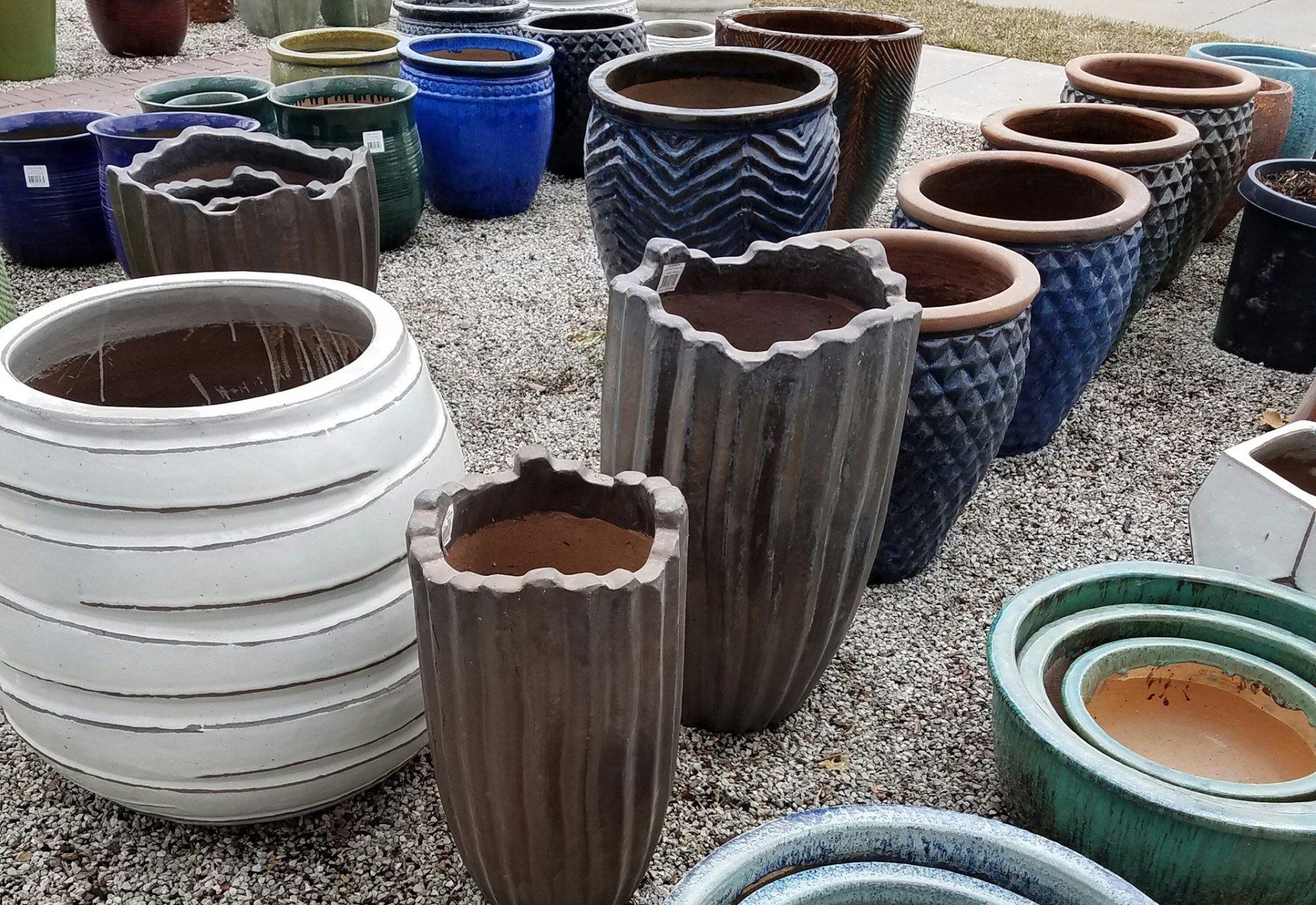 A bunch of different colored pots are sitting on the ground.