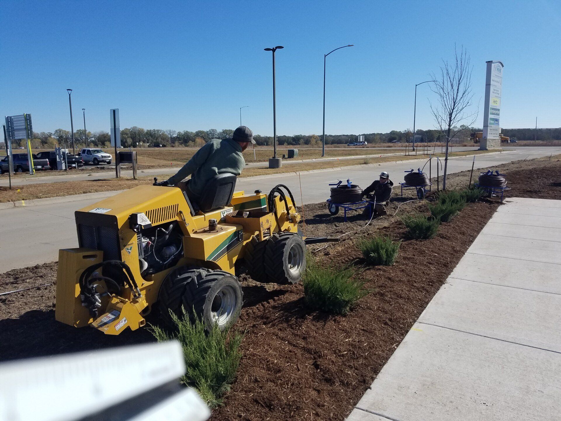 A man is riding a yellow tractor on a sidewalk.