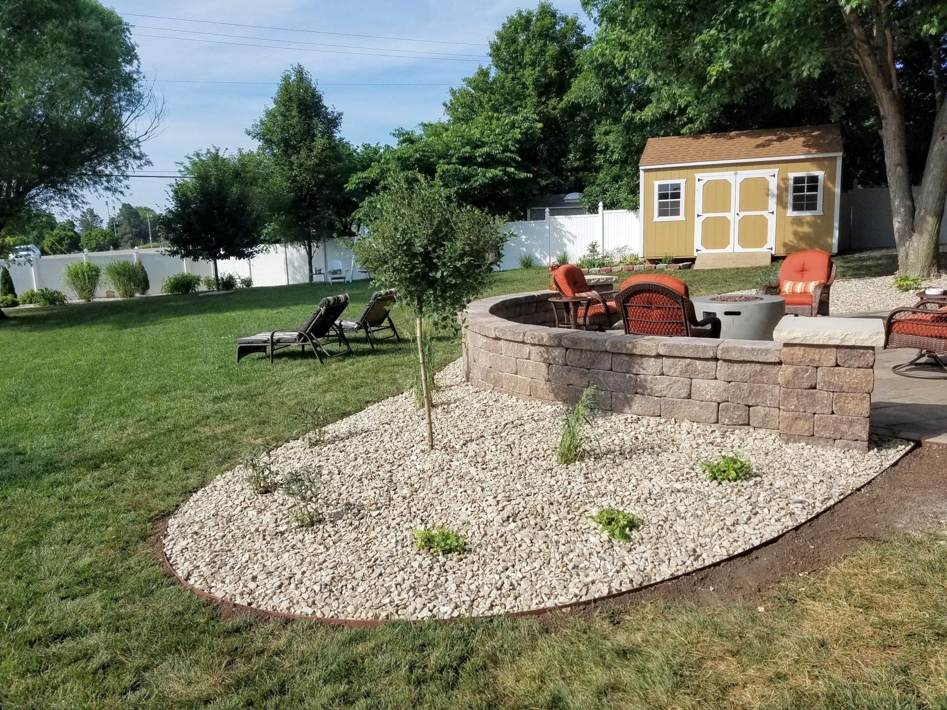 A backyard with a fire pit and a shed in the background
