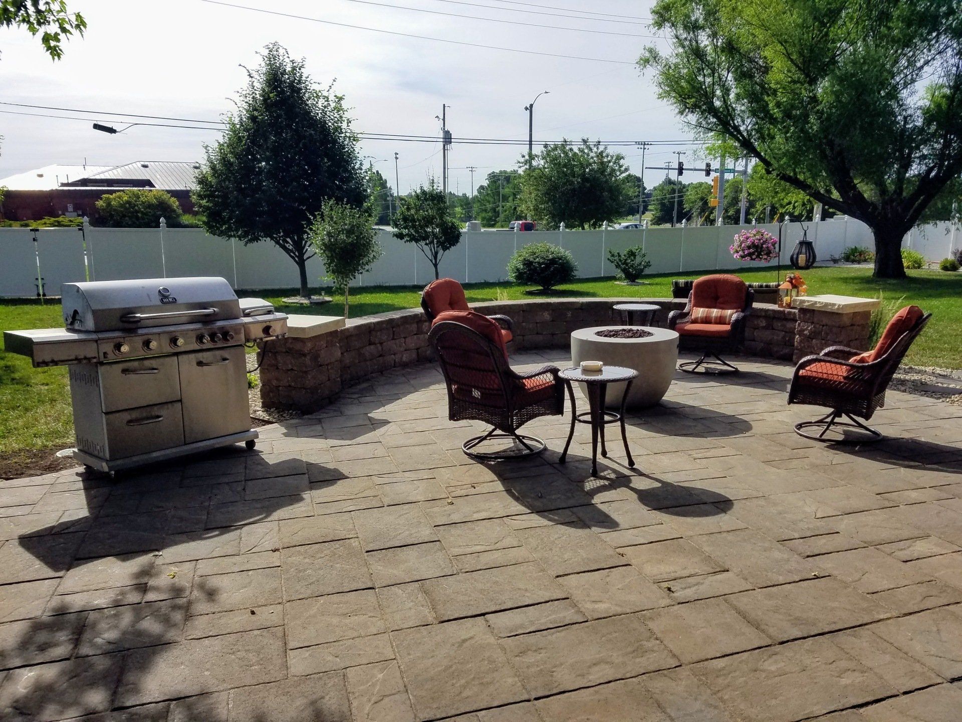 A patio with a grill and chairs and a fire pit