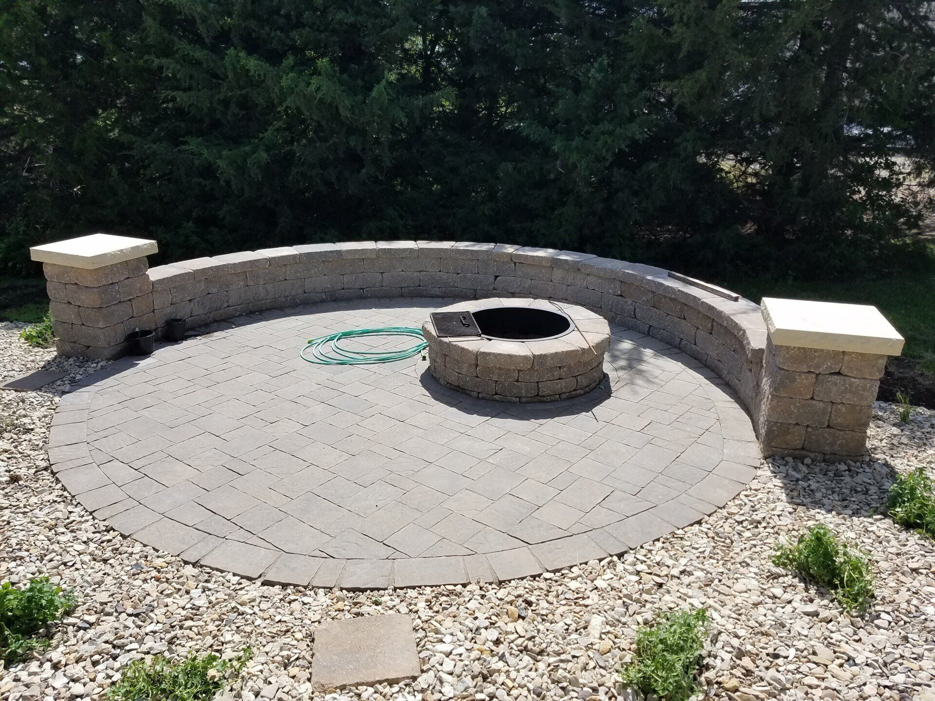 A fire pit is surrounded by a stone wall and gravel