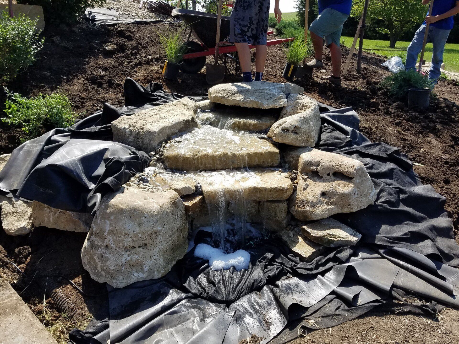 A group of people are working on a waterfall in a garden.