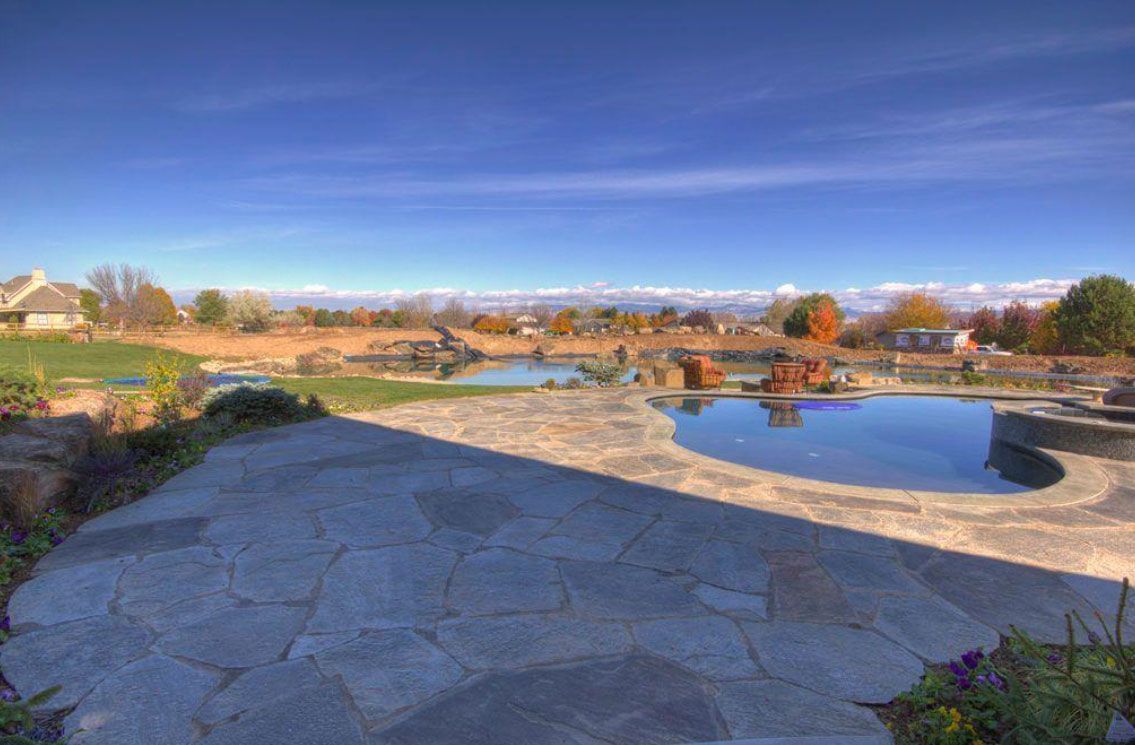 Patio with two pools and distant hills under a bright blue sky.