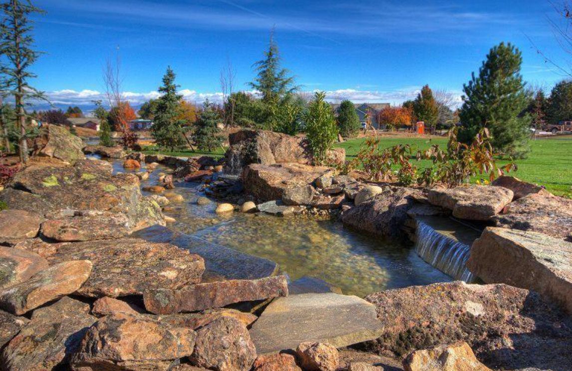 A shallow stream flows through a rocky landscape under a blue sky.