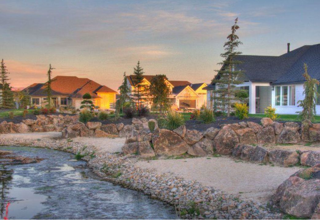 Houses at sunset, with a man-made stream in the foreground.