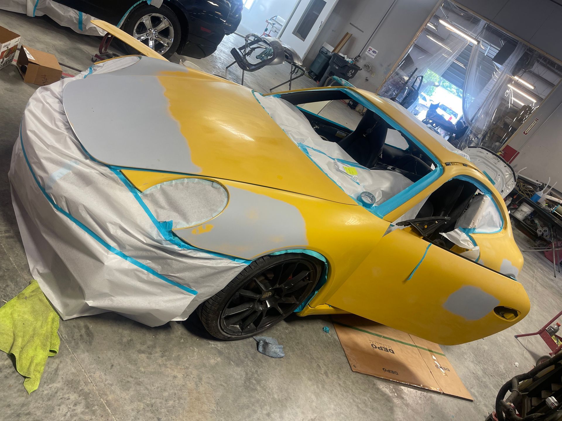 A yellow car is being painted in a garage.
