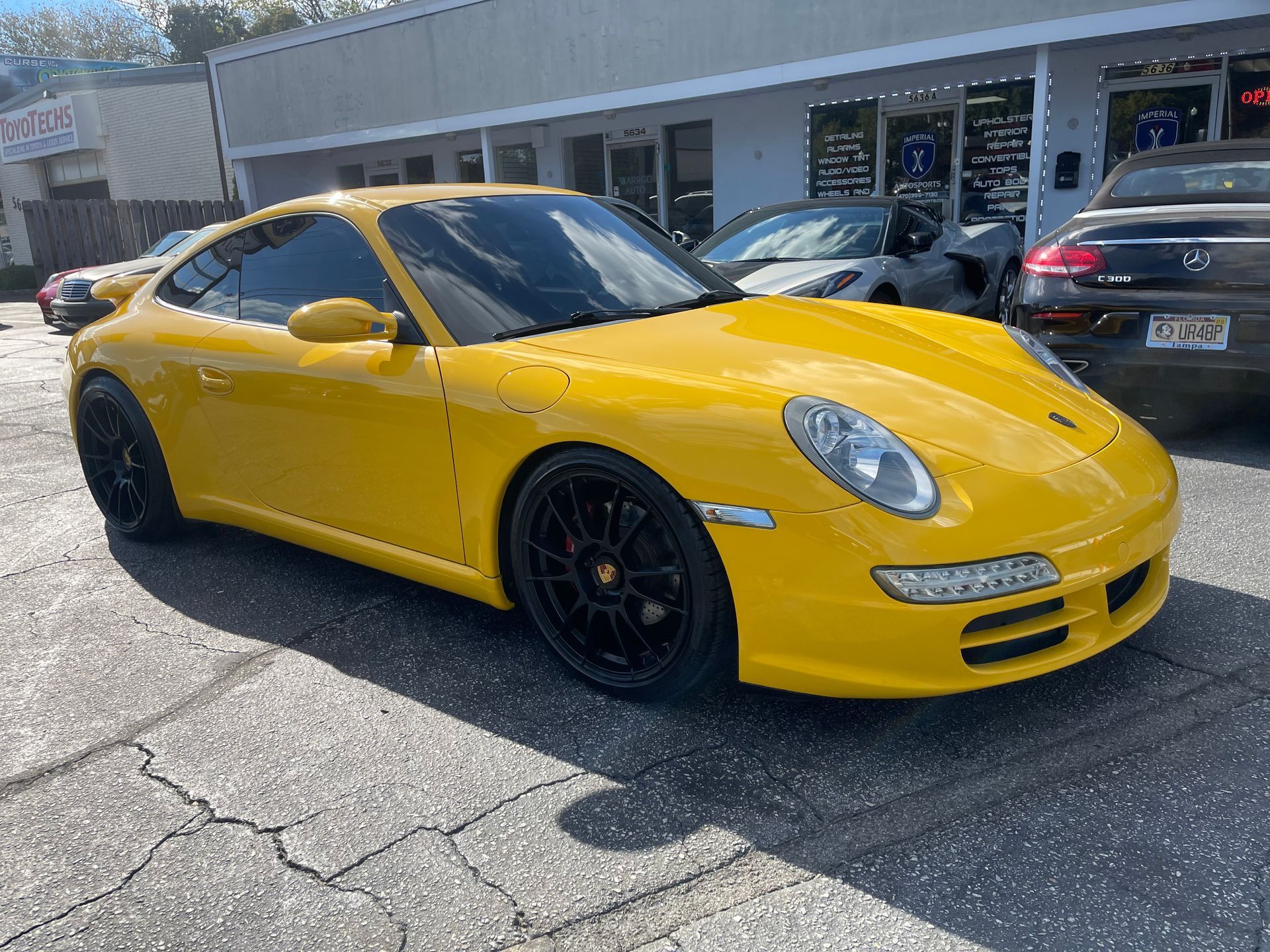 A yellow Porsche 911 is parked in front of a building.