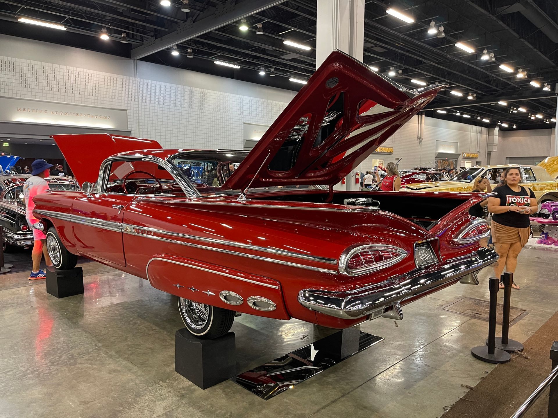 A red car with the hood up is on display at a car show.