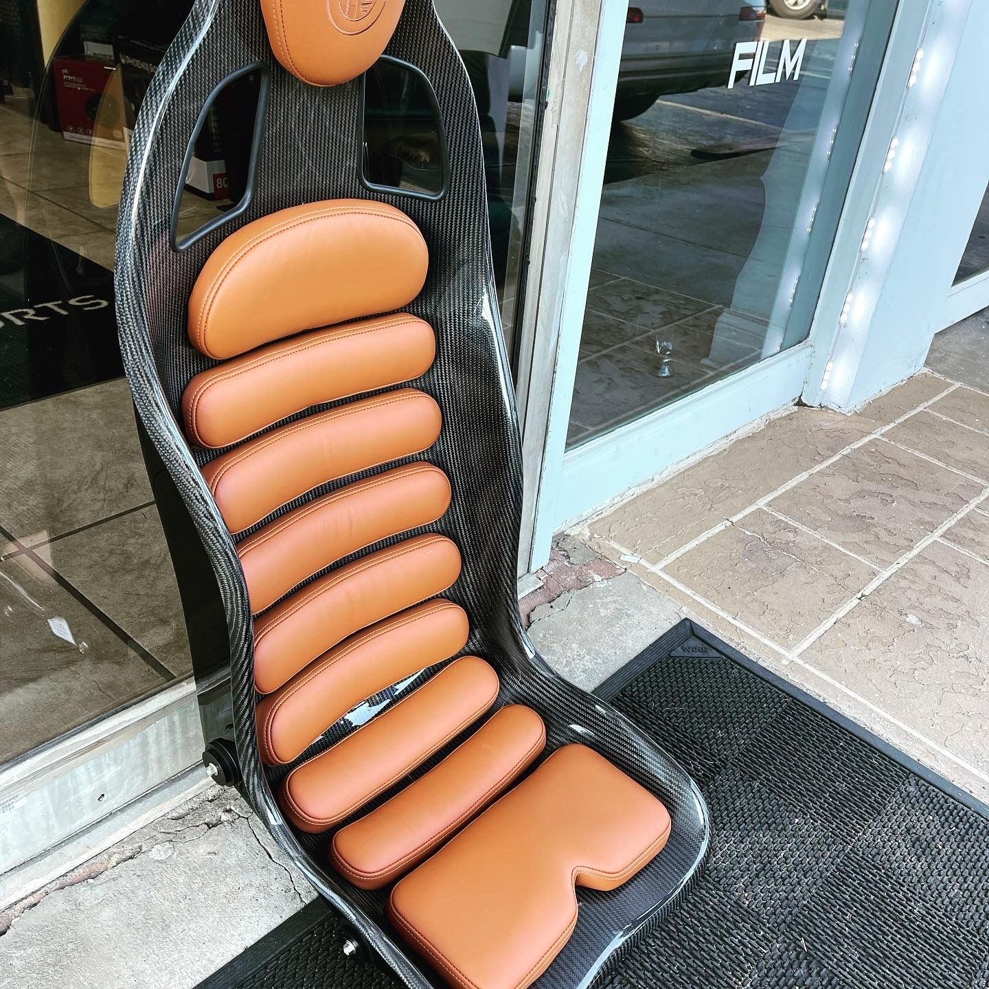 A chair with brown cushions is sitting in front of a glass door.